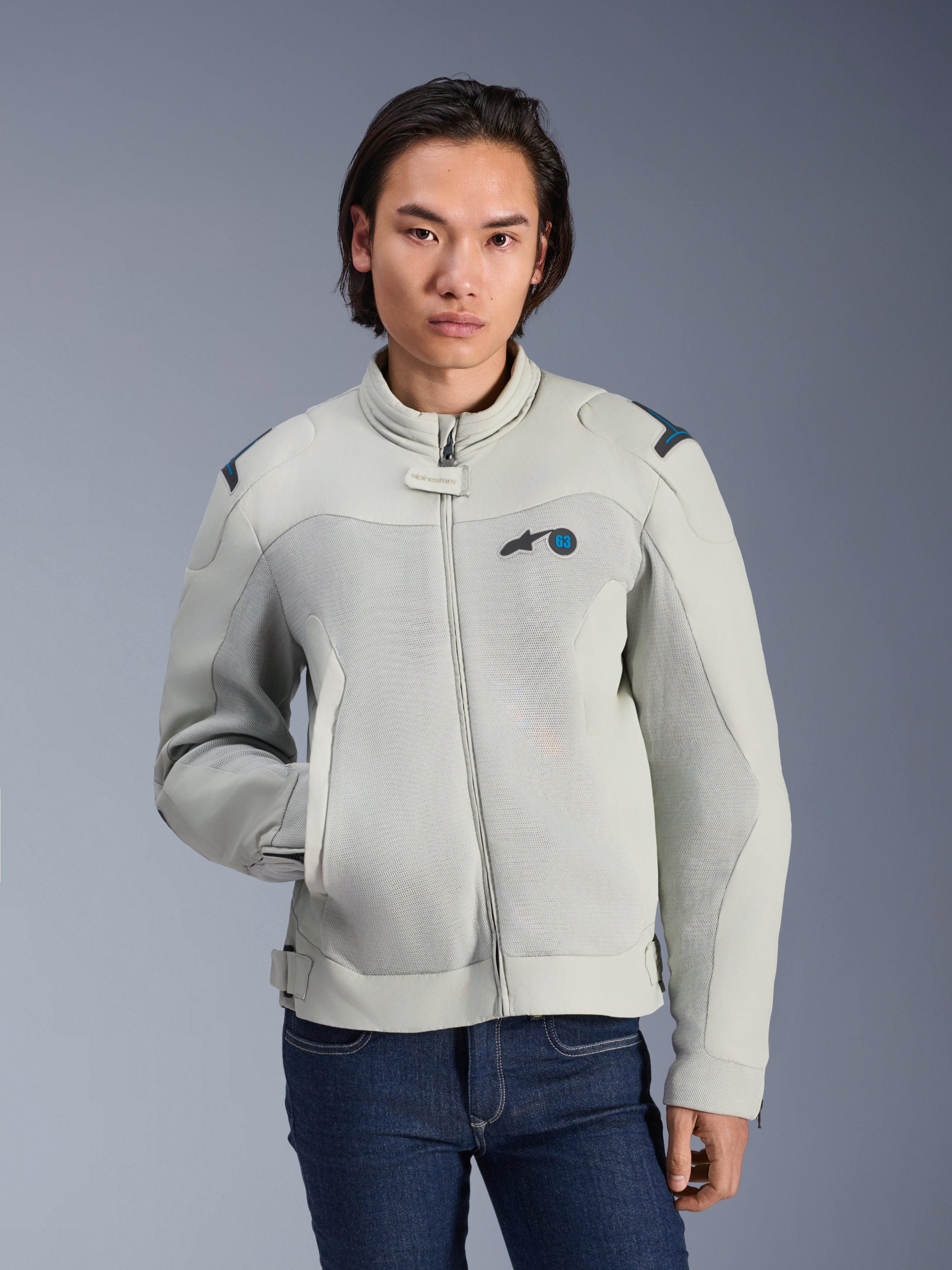 Veste Alpinestars Circal-1 Air, Gris métal et Bleu méthyle, veste de moto urbaine avec panneaux en maille aérée, fermeture éclair frontale et col rembourré, portée par un mannequin avec un jean bleu, design futuriste et durable pour la conduite estivale