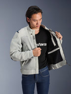 Veste Alpinestars Circal-1 Air, Gris Métal, maintenue ouverte pour montrer la doublure intérieure en maille et les détails des poches, portée par un mannequin avec un t-shirt noir à logo et un jean bleu, style moto urbain