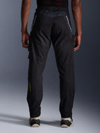 Alpinestars Acteon Pants, Urban Motorcycle Pants, Black, rear view showing tapered fit, white branding on upper legs and yellow logo on the lower calf, adjustable leg openings with zippers, worn with cream sneakers