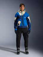 Veste Alpinestars Mogress Air, veste de moto urbaine Bleu Amande, portée avec un pantalon et des bottes noirs, présentant un design technique color-block bleu et crème avec des poches utilitaires et une capuche, vêtement de moto contemporain d'inspiration streetwear