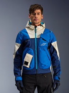 Alpinestars Mogress Air Jacket en Blue Almond, veste de moto urbaine à capuche avec empiècements contrastés bleus et blanc cassé, poches utilitaires et fermeture éclair frontale turquoise, portée par un mannequin avec un pantalon et des gants noirs