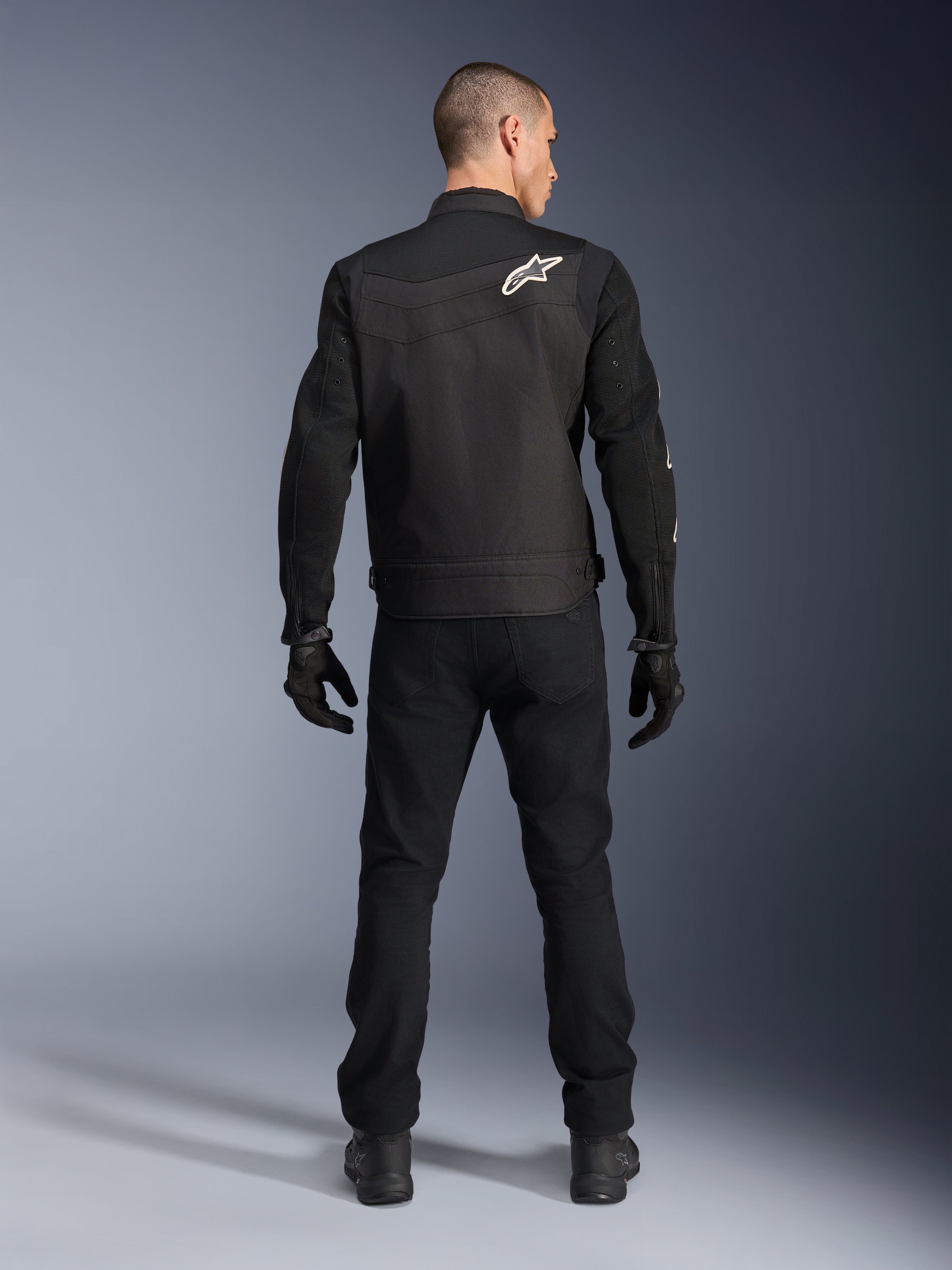 Alpinestars T-Dyno Air Jacket, Black, Rear view on model, Textile motorcycle jacket featuring 3D mesh panels and a white star logo on the shoulder, worn with black pants and gloves, modern urban riding outfit