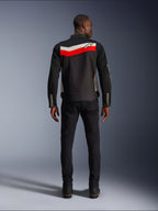 Veste Alpinestars T-Dyno Air, veste de moto textile pour homme, vue arrière, noire avec bandes horizontales rouge vif et écru dans le dos, logo Alpinestars sur l'empiècement, portée avec un pantalon et des bottes noirs, construction en maille 3D respirante