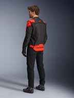 Homme portant la veste Alpinestars T-Stunt Air vue de dos, Noir Rouge Fluo et Rouge Foncé, veste de moto en textile avec panneaux en mesh et coupe sportive, avec le logo Alpinestars imposant dans le bas du dos, associée à un pantalon noir et des bottes de moto