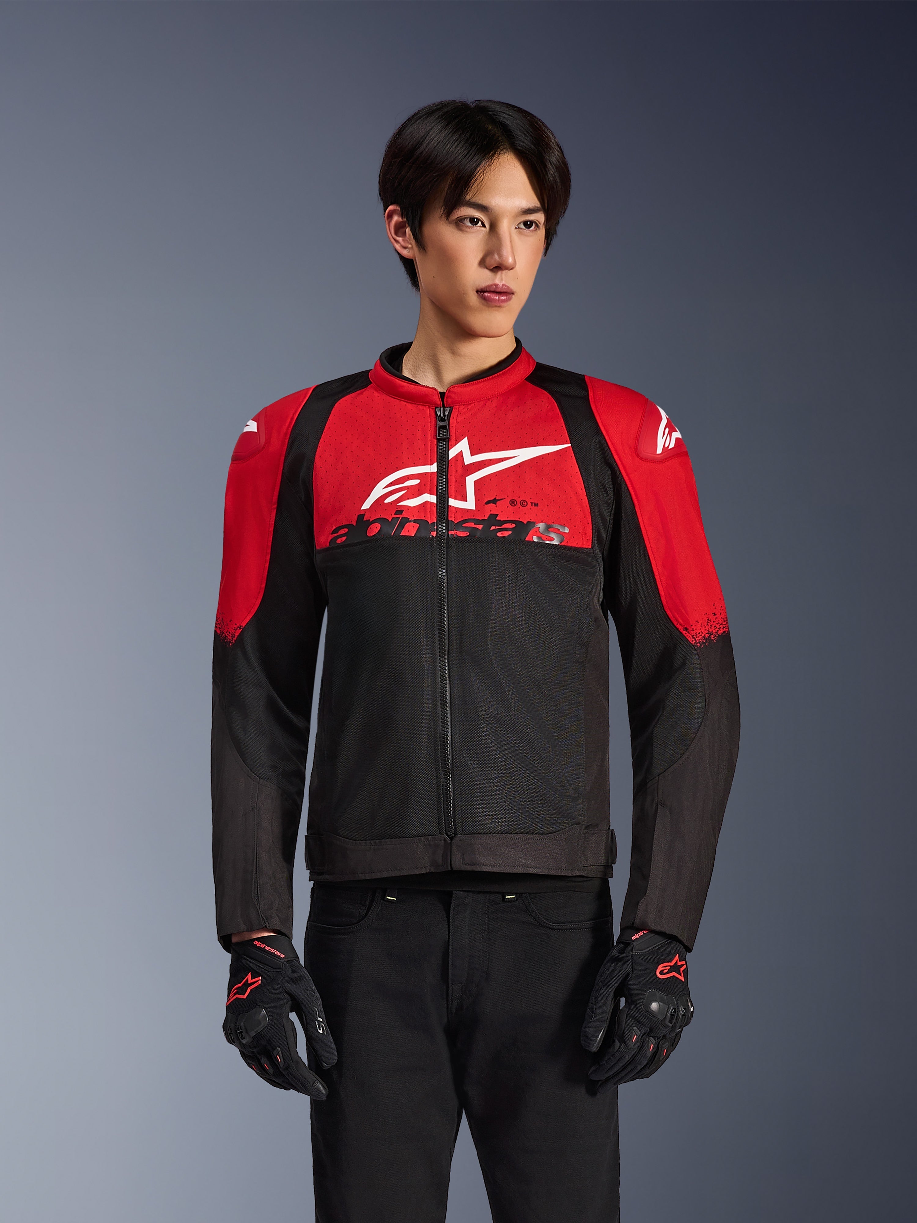 Alpinestars SMX Air Jacket, veste de moto en mesh, rouge vif et noir, portée par un mannequin avec des gants de moto noirs, arborant un large logo blanc sur la poitrine, construction en textile ventilé avec panneaux rouges aux épaules et manches noires, équipement de performance sportif pour la conduite par temps chaud
