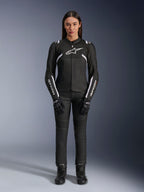 Veste Alpinestars Stella T-Sps Air V2, veste de moto pour femme, noir et blanc, avec panneaux en mesh et détails blancs, portée avec un pantalon, des gants et des bottes noirs, coupe athlétique pour une conduite urbaine