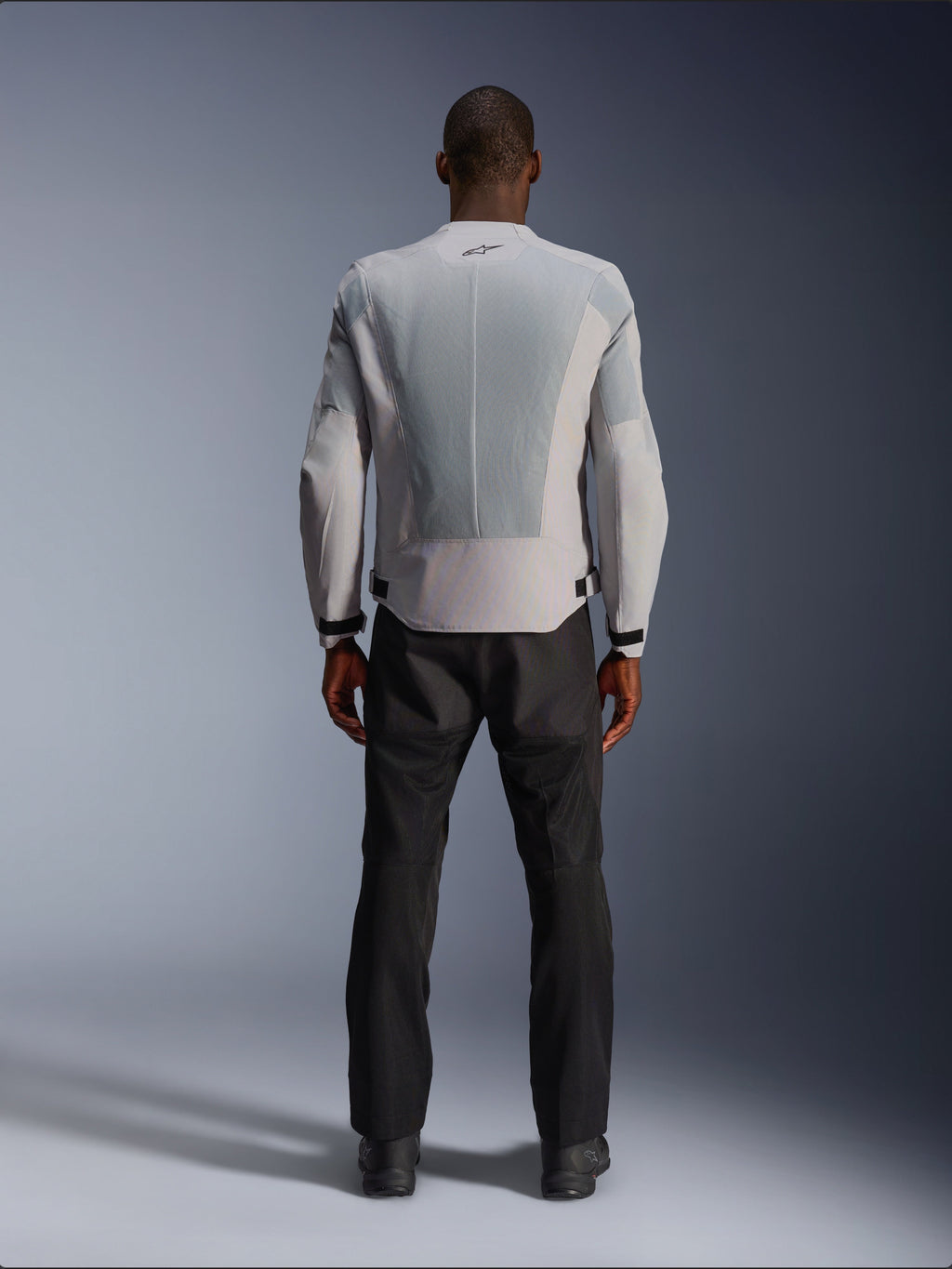 Veste Alpinestars C-1 Air en Silver, vue de dos sur un mannequin homme, veste de moto en textile dotée de larges panneaux de ventilation en maille technique, petit logo noir au niveau du col et ajusteurs de taille, portée avec un pantalon de moto noir pour un style urbain contemporain.
