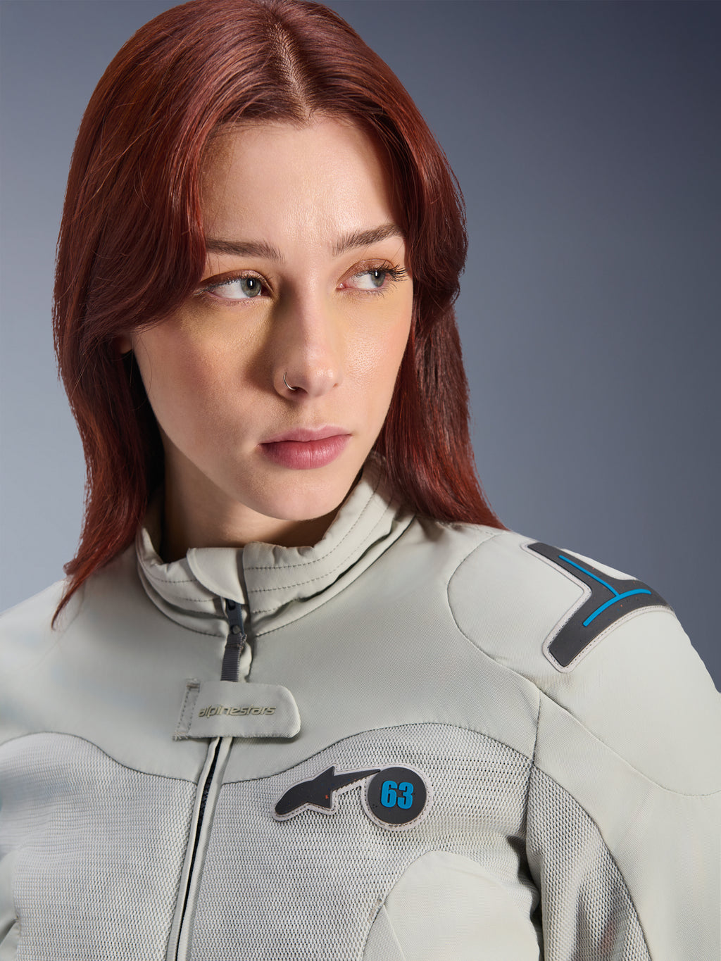 Femme portant la veste Alpinestars Stella Circal-1 Air, veste de moto textile pour femme, coloris Metal Gray et Methyl Blue, gros plan lifestyle avec panneaux en mesh pour le flux d'air, col rembourré et patch logo Alpinestars avec le numéro 63