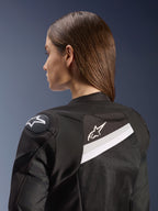 Veste Alpinestars Stella T-GP Plus R V4 Airflow, veste de moto sport pour femme, noir et blanc, avec panneaux arrière en mesh et accents blancs, logo Alpinestars sur l'épaule et le dos, coupe anatomique pour la conduite sportive