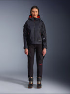 Pantalon femme Alpinestars Actea, pantalon de moto noir avec détails de texte rouges et poches cargo, porté par une motarde avec une veste à capuche noire, tenue de moto urbaine moderne