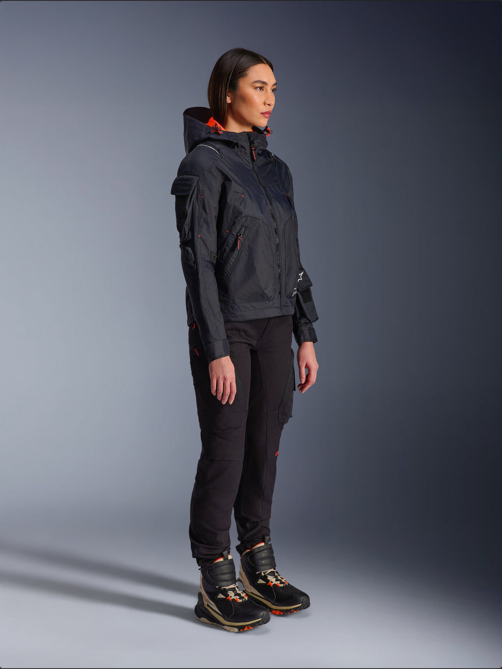 Pantalon femme Alpinestars Actea noir, coupe régulière avec poches cargo, associé à une veste Molly Air noire aux accents orange et des chaussures de moto montantes, vêtements de moto urbains contemporains pour femmes
