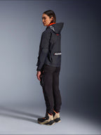Pantalon femme Alpinestars Actea, noir, pantalon de moto moderne avec coupe fuselée et poche cargo sur la cuisse, vue de profil arrière sur un mannequin portant une veste à capuche sombre et des bottes de moto, style urbain