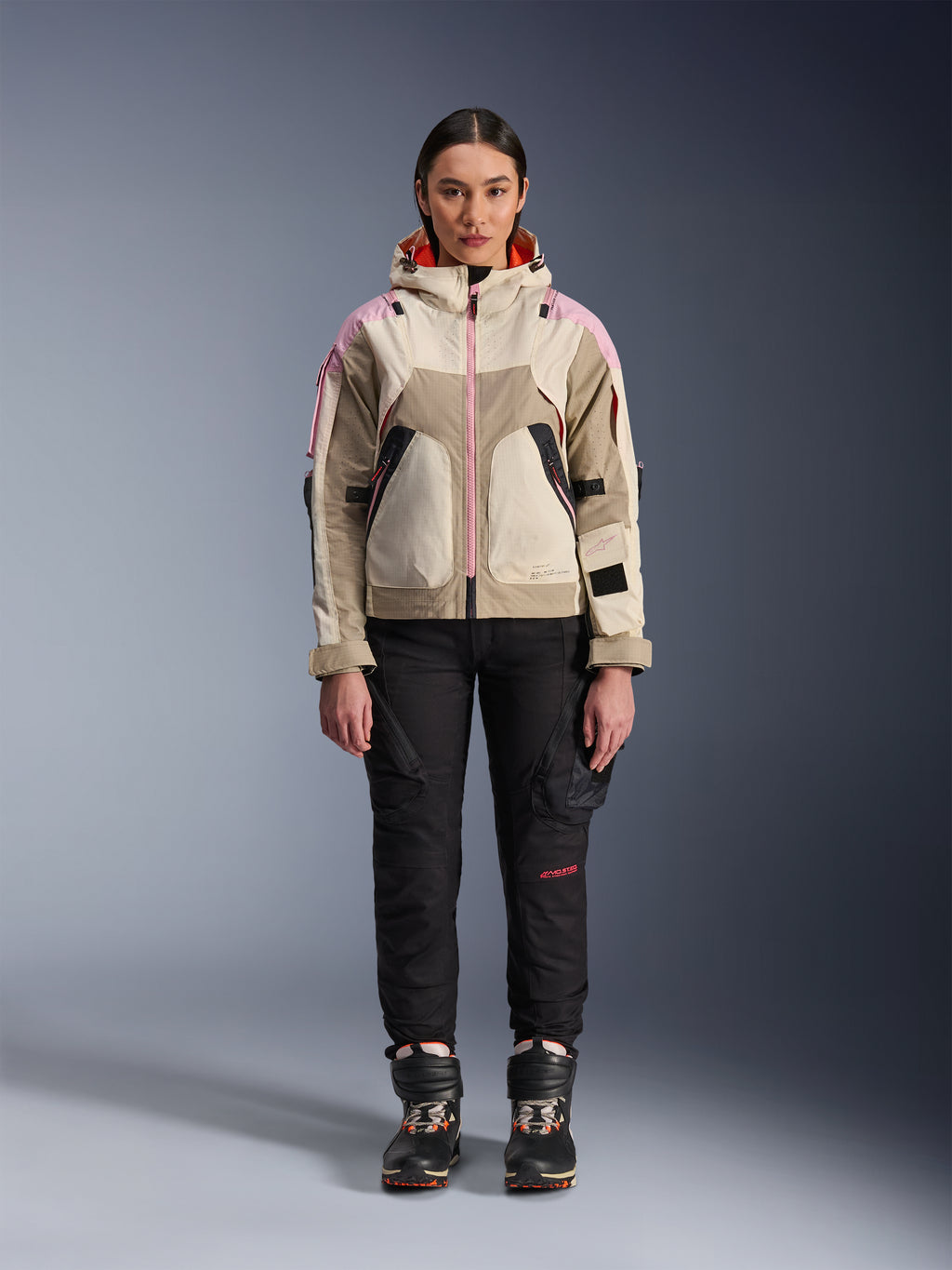 Mannequin femme portant la veste Alpinestars Molly Air en Sand Pink Almond, avec un pantalon de moto technique noir et des bottes, vue de face en pied, veste de moto urbaine au design d'inspiration utilitaire et accents roses