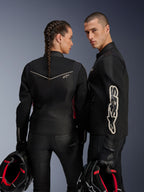 Motards homme et femme portant des vestes Alpinestars Stella T-Dyno Air et vestes homme assorties, textile noir avec panneaux en maille 3D et accents rouge fuchsia, tenant des casques en studio, équipement de moto urbain contemporain.