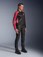 Veste Alpinestars Stella T-Dyno Air, veste de moto pour femme, noire avec rayures rouge vif et fuchsia sur les manches, portée avec un pantalon de moto et des bottes noirs, design en maille d'inspiration vintage pour la conduite urbaine