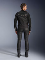 Veste Alpinestars Stella T-Dyno Air, vue arrière, veste de moto noire pour femme avec liseré blanc et petit logo étoile, portée avec un pantalon technique noir et des bottes de moto, coupe biker élégante pour la conduite urbaine