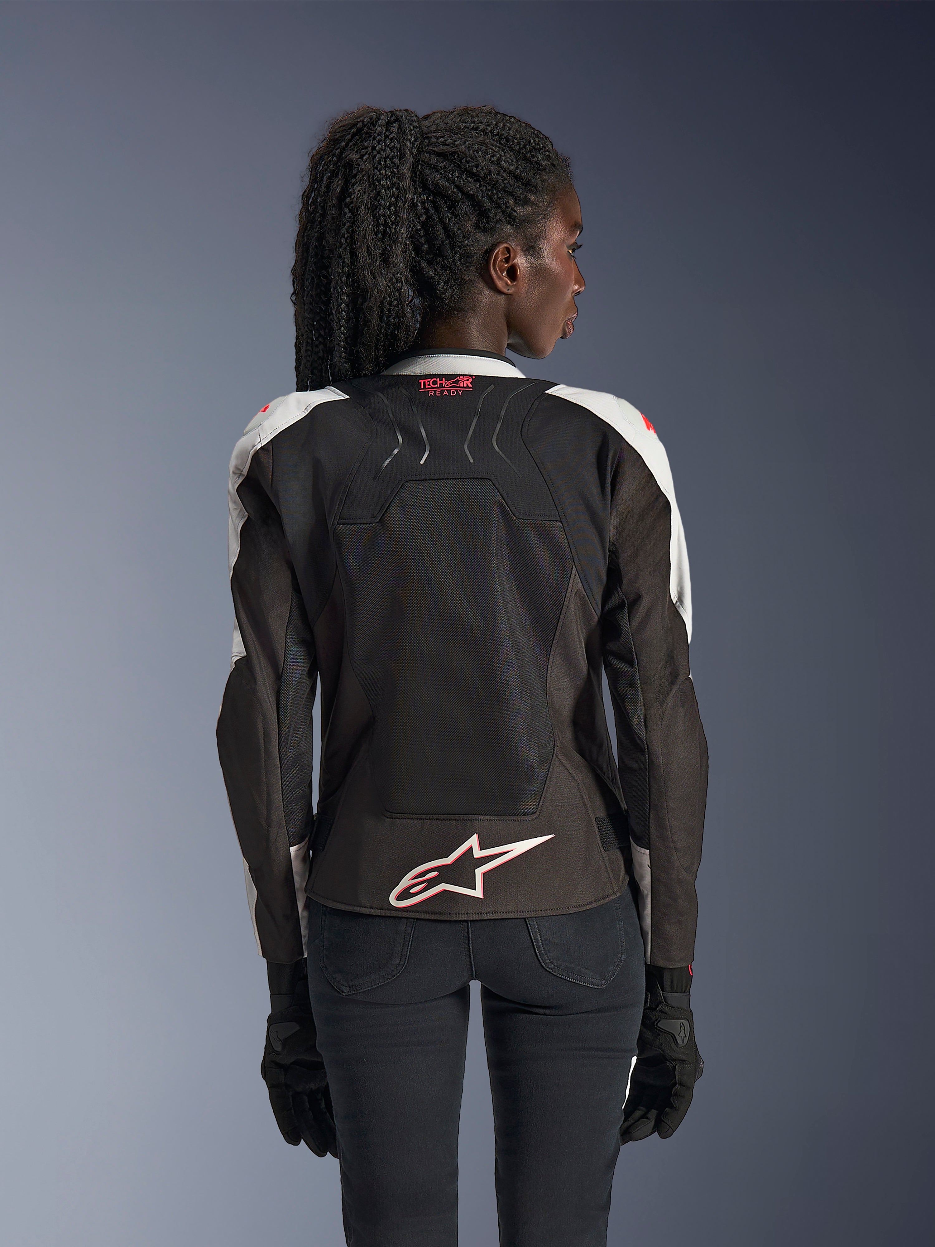 Veste Alpinestars Stella SMX Air, veste de moto pour femme, gris glacé et noir avec accents corail fluo, vue arrière montrant le marquage Tech-Air Ready et le logo Astar blanc, châssis en mesh pour une ventilation élevée, coupe de style sportif