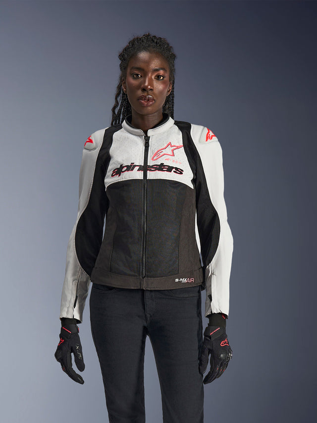 Veste Alpinestars Stella SMX Air pour femme, Ice Gray, Noir et Corail Fluo, construction en mesh et panneaux perforés, portée par un mannequin avec gants et pantalon de moto noirs, vue de face.