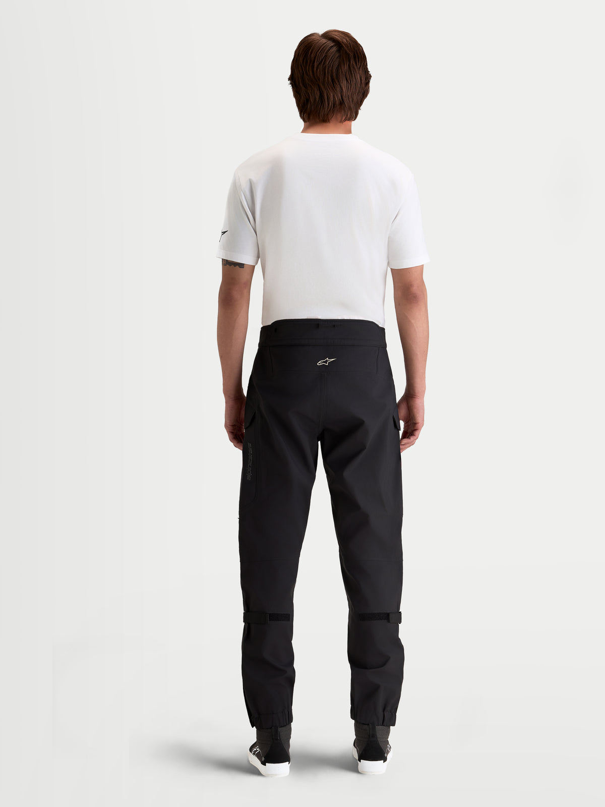 Alpinestars Juggernaut V2 Drystar® Pants, men's waterproof urban motorcycle pants in black, rear view showing high-back waistband and technical textile construction worn by a model.