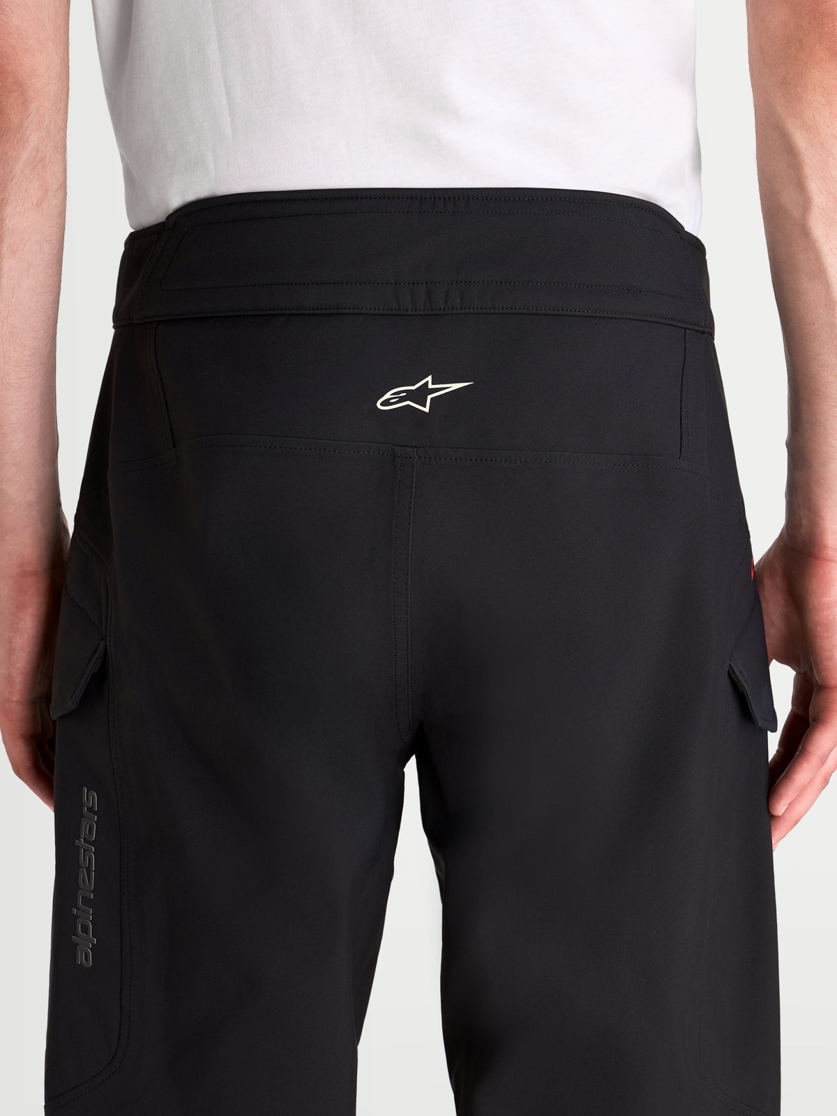 Alpinestars Juggernaut V2 Drystar® Pants, men's waterproof urban motorcycle pants in black, rear view showing high-back waistband, white Astar logo, and cargo pockets worn by a model