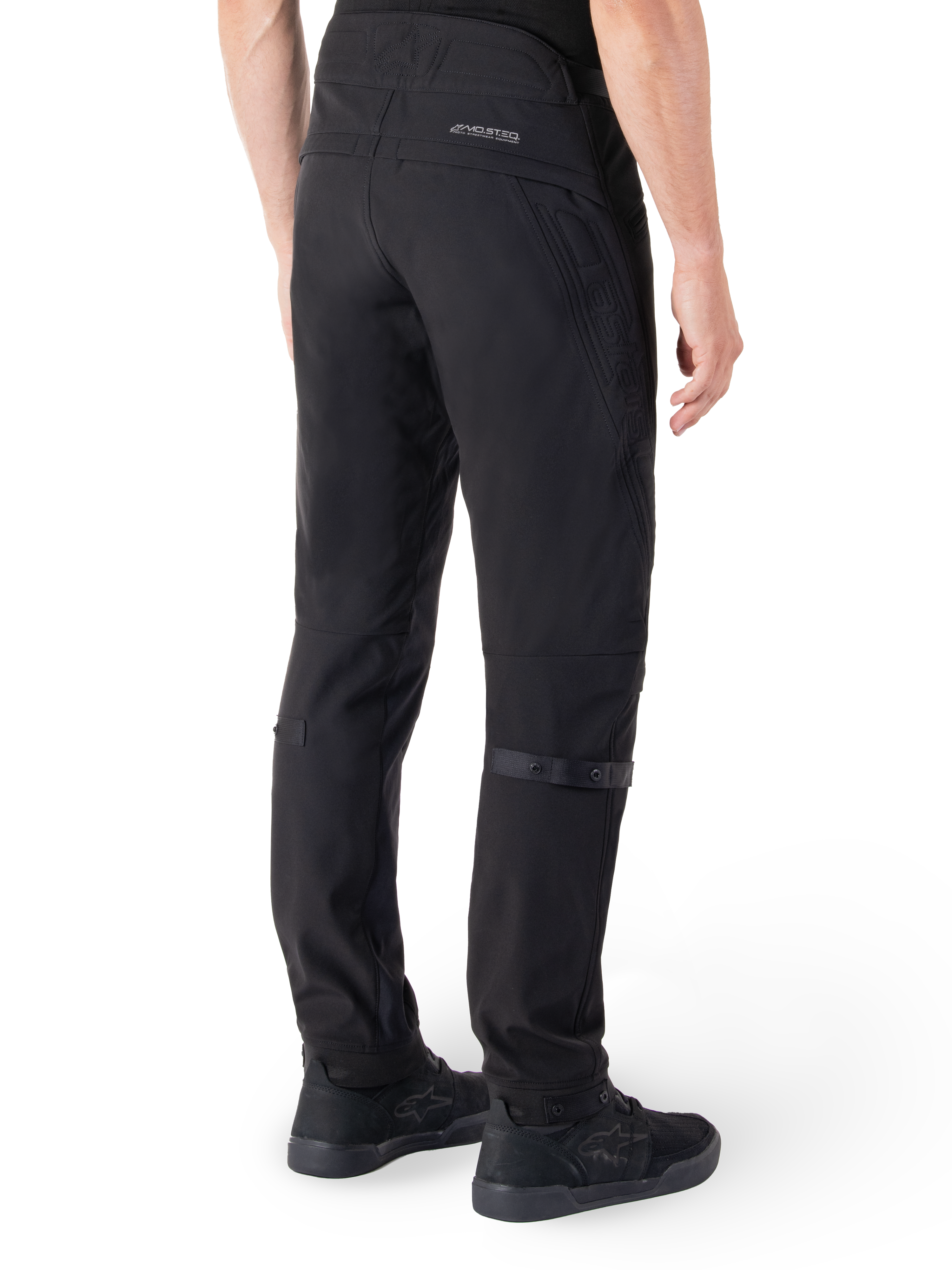 Alpinestars Alden Pants, Urban Motorcycle Pants, Black, rear view showing technical softshell fabric with quilted details, MO.ST.EQ. reflective branding on the back yoke, and adjustable calf straps, paired with black riding shoes