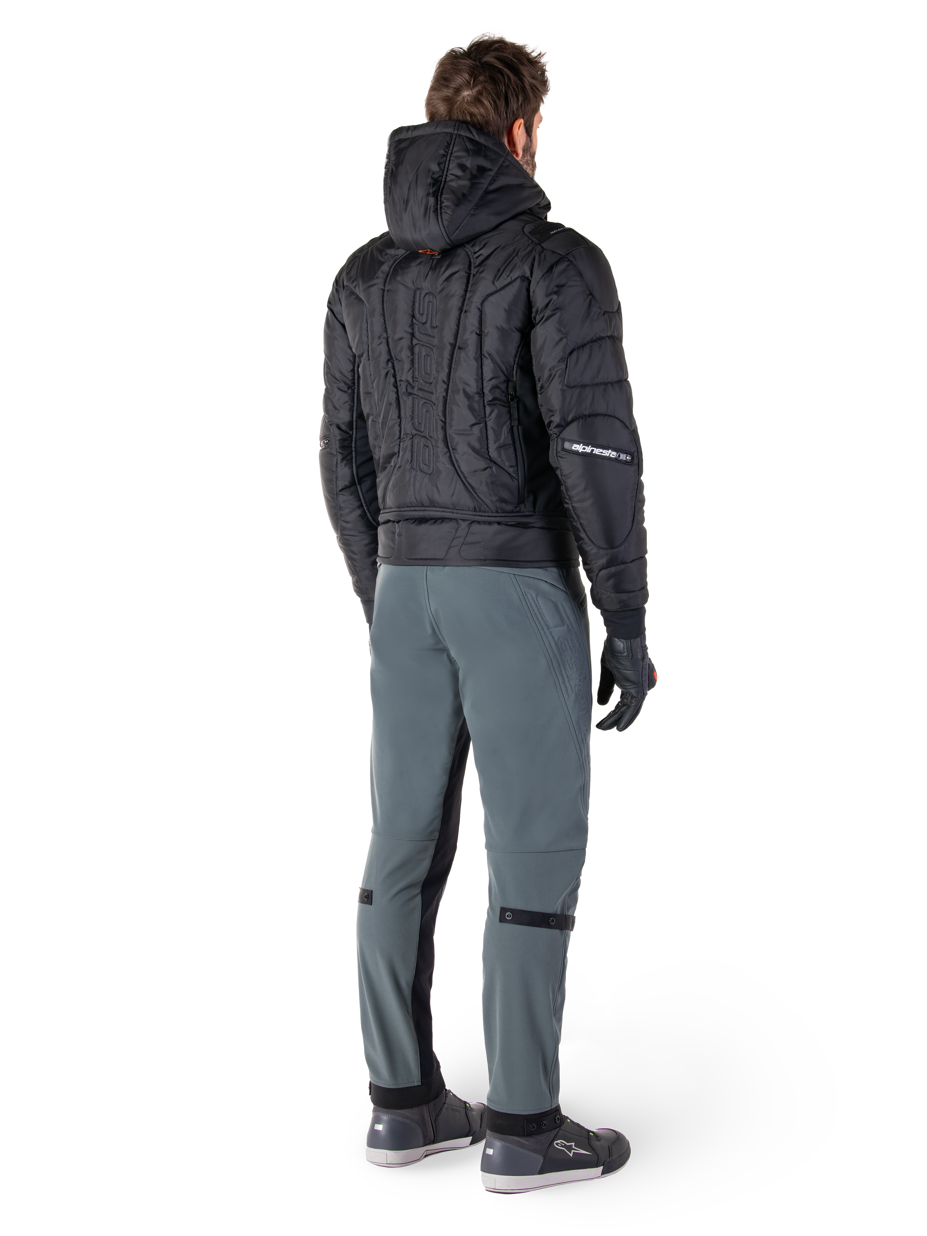 Pantalon Alpinestars Alden, pantalon de moto urbain, Gris Urbain, vue arrière d'un pilote portant une veste à capuche matelassée noire et des baskets de moto, coupe ajustée sous le genou avec panneaux extensibles noirs et ajusteurs aux genoux, design moderne d'inspiration streetwear