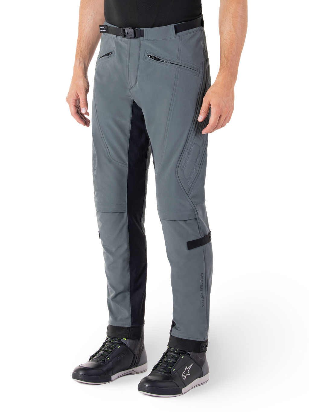 Pantalon Alpinestars Alden, pantalon de moto gris urbain et noir, pantalon de moto en textile inspiré du streetwear avec softshell extensible à 3 couches, empiècements noirs à l'intérieur des jambes, ceinture intégrée, coupe ajustée sous le genou, porté avec des chaussures de moto noires