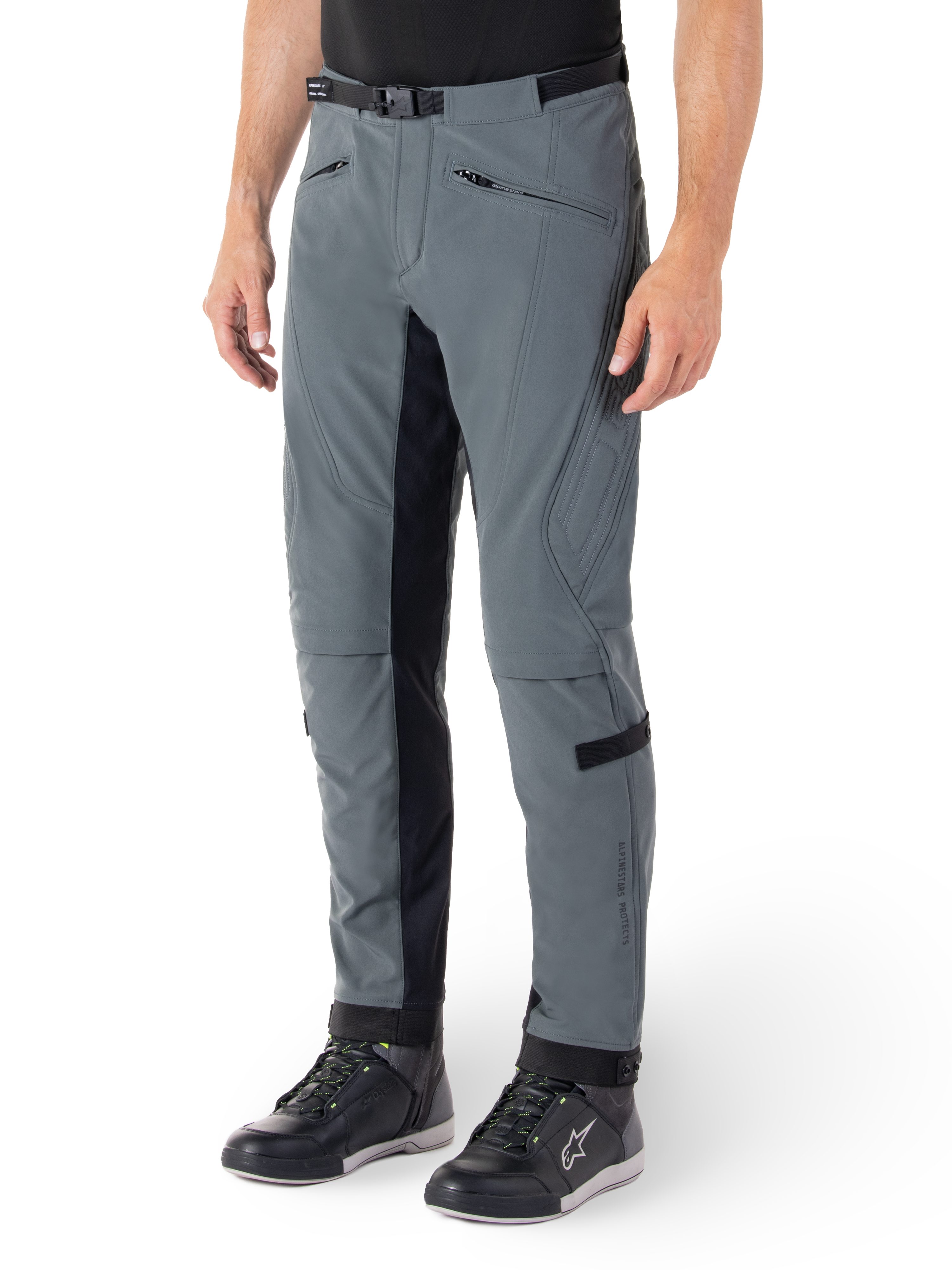 Pantalon Alpinestars Alden, pantalon de moto gris urbain et noir, pantalon de moto en textile inspiré du streetwear avec softshell extensible à 3 couches, empiècements noirs à l'intérieur des jambes, ceinture intégrée, coupe ajustée sous le genou, porté avec des chaussures de moto noires