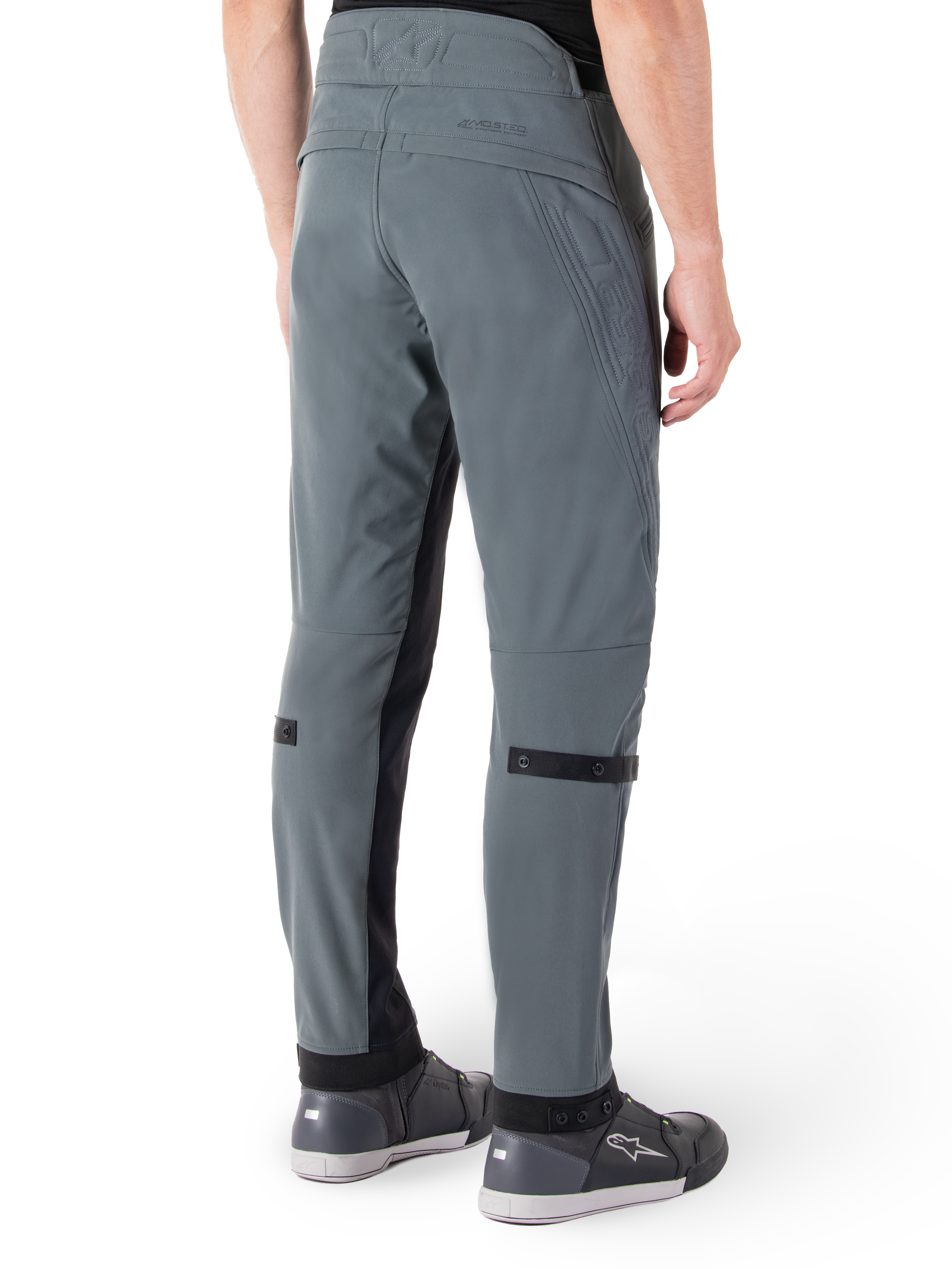 Pantalon Alpinestars Alden, Gris Urbain, vue latérale arrière, pantalon de moto technique d'inspiration streetwear avec détails matelassés à la taille et sangles noires aux mollets, associé à des chaussures de moto grises, équipement de moto urbain moderne