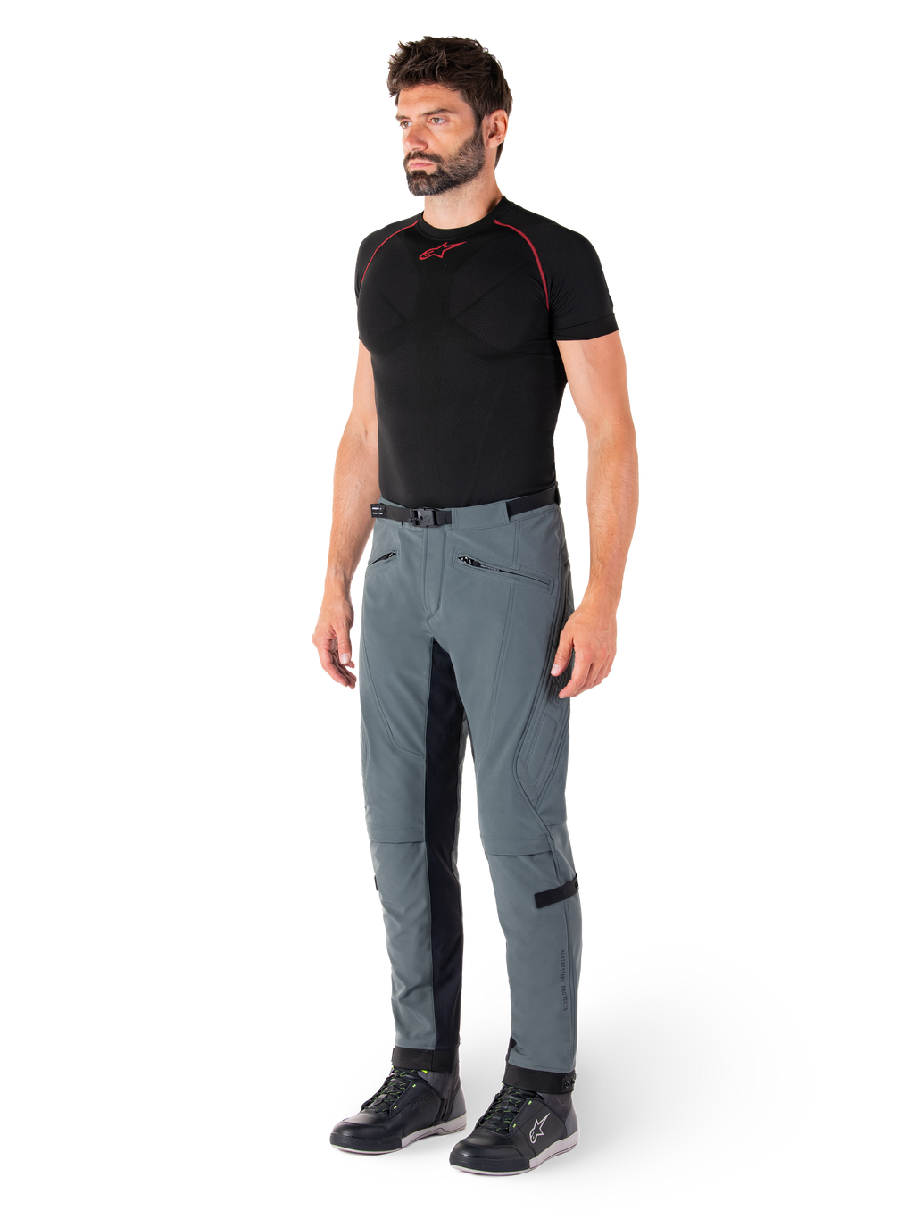 Pantalon Alpinestars Alden, pantalon de moto technique gris urbain, avec empiècements latéraux matelassés et tissu extensible noir à l'intérieur des jambes, porté avec une couche de base noire et des chaussures de moto, équipement de conduite urbaine d'inspiration streetwear
