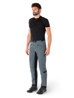 Pantalon Alpinestars Alden, pantalon de moto technique gris urbain, avec empiècements latéraux matelassés et tissu extensible noir à l'intérieur des jambes, porté avec une couche de base noire et des chaussures de moto, équipement de conduite urbaine d'inspiration streetwear