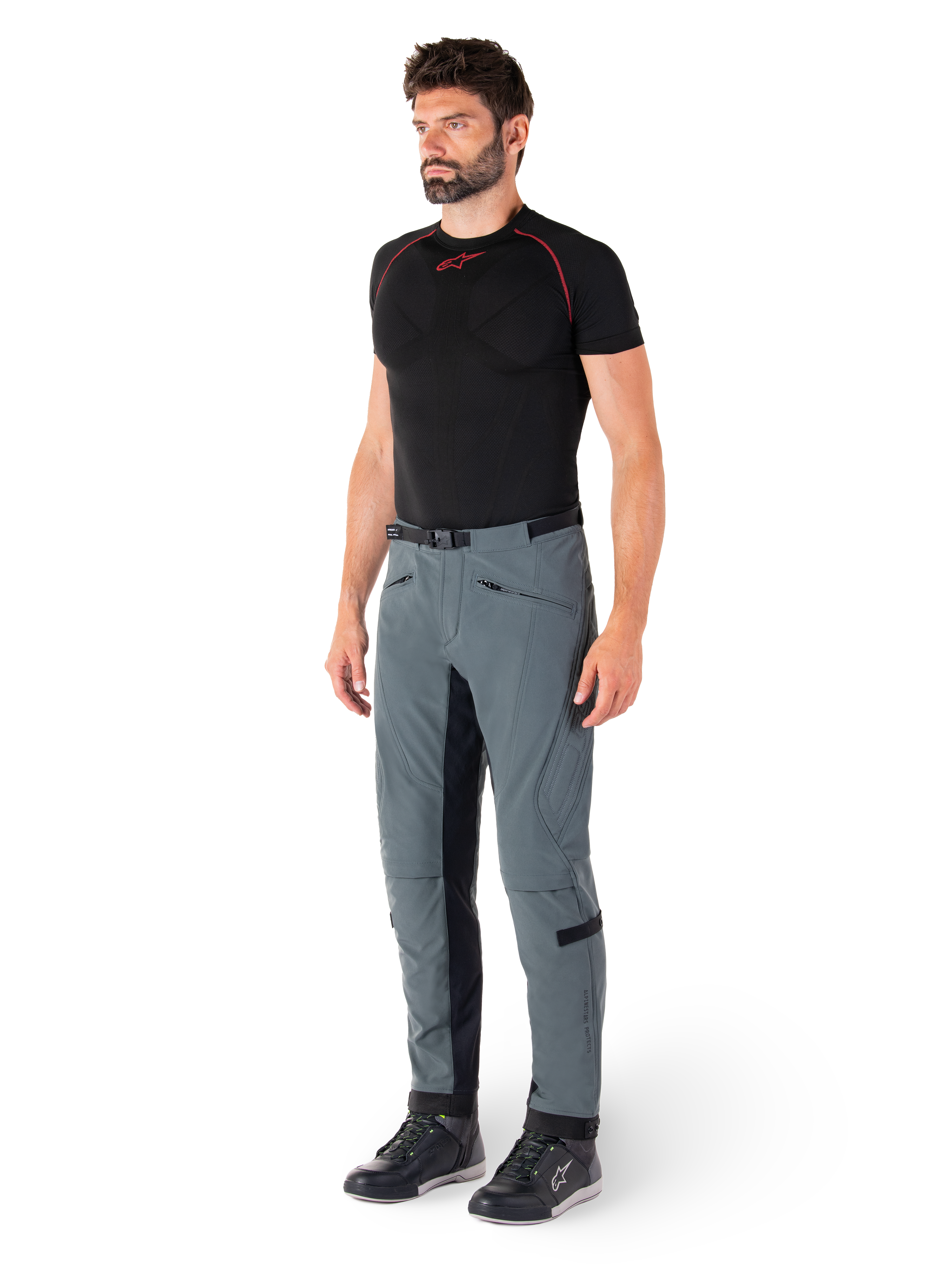 Pantalon Alpinestars Alden, pantalon de moto technique gris urbain, avec empiècements latéraux matelassés et tissu extensible noir à l'intérieur des jambes, porté avec une couche de base noire et des chaussures de moto, équipement de conduite urbaine d'inspiration streetwear