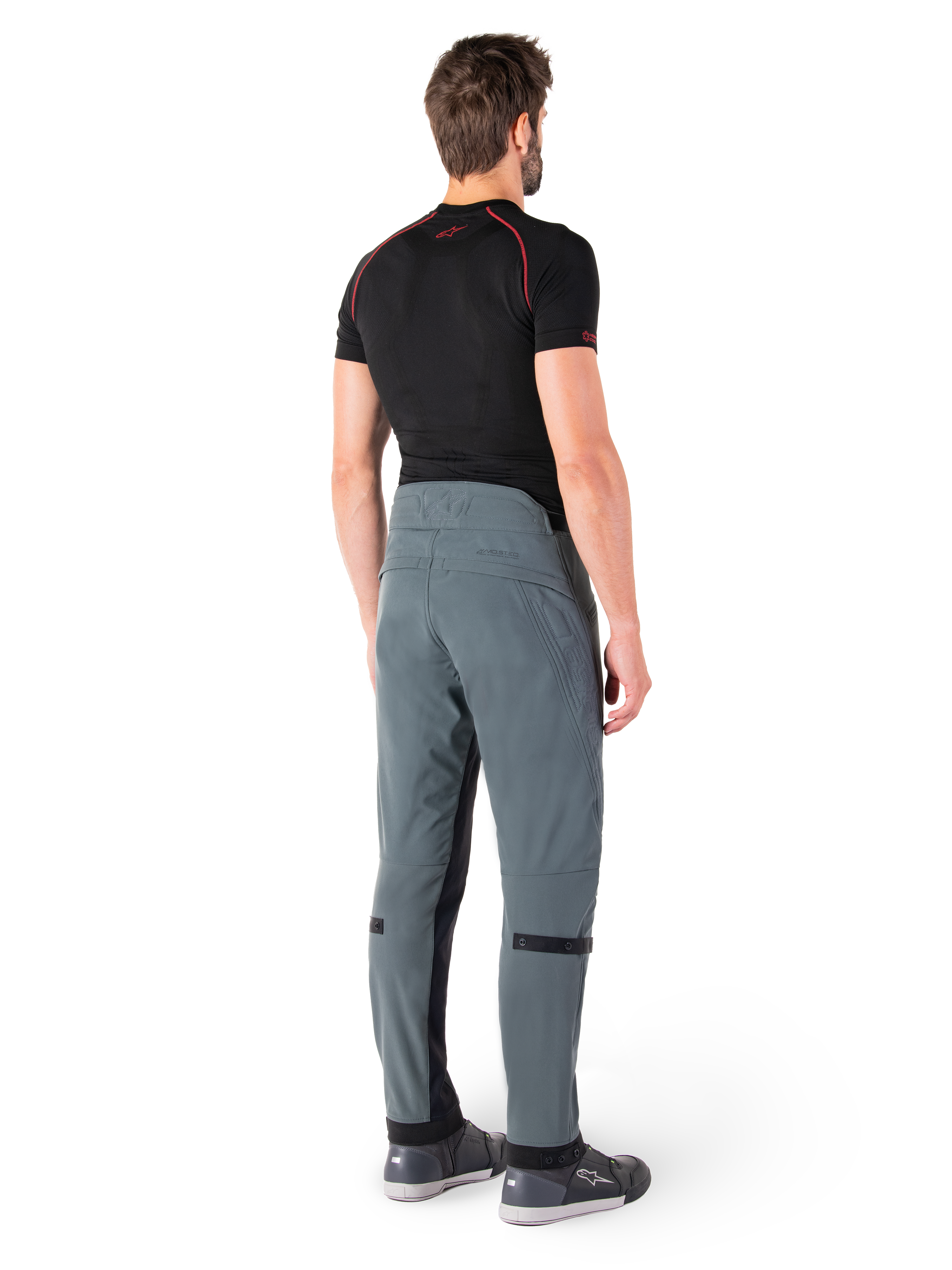 Pantalon Alpinestars Alden, Urban Gray, vue arrière, pantalon de moto en textile technique avec détails matelassés sur le haut de la taille arrière et les jambes, associé à une couche de base noire et des chaussures de moto grises, style streetwear urbain contemporain.