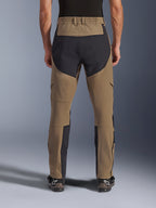 Pantalon Alpinestars Flex-AST Explorer, pantalon de moto aventure, Walnut Black, vue arrière porté par un pilote, panneaux de renfort en ripstop noir sur l'assise et l'intérieur des jambes, taille élastiquée, longues fermetures éclair au bas des jambes et bottes d'aventure assorties