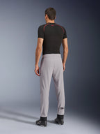 Vue arrière d'un mannequin portant le pantalon Aeroshell Airflow d'Alpinestars en Mid Gray, associé à un haut de couche de base noir et des chaussures noires, mettant en évidence les zones perforées au laser sur les mollets et la coupe sportive athlétique.