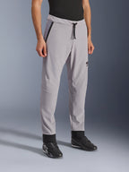 Pantalon Alpinestars Aeroshell Airflow, gris moyen, pantalon de moto léger avec zones de ventilation perforées au laser sur les cuisses et les tibias, doté d'une taille élastique avec cordon de serrage et d'une coupe sport ajustée, porté par un mannequin avec des chaussures de moto noires.