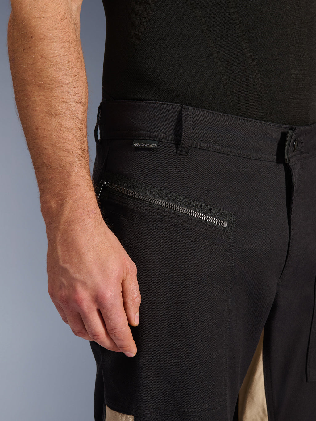 Pantalon Alpinestars Flex-AST Canvas en Black Aluminum, vue rapprochée de la zone des hanches avec une poche de conduite horizontale zippée, des passants de ceinture et une petite étiquette de marque, construction durable en polycoton extensible pour la conduite urbaine.