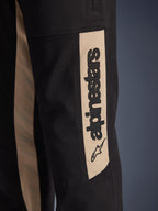 Pantalon Alpinestars Flex-AST Canvas, gros plan sur le côté de la jambe, noir avec panneau d'accentuation couleur aluminium, arborant un logo Alpinestars vertical noir et une icône d'étoile, sergé de polycoton résistant pour la conduite moto urbaine