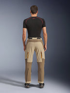 Alpinestars Maxdura Dual Pants in Walnut Aluminum, rear view showing two-tone brown and tan design, adventure riding pants with zippered cargo pockets and reinforced seat, worn with a black compression shirt and motorcycling boots.