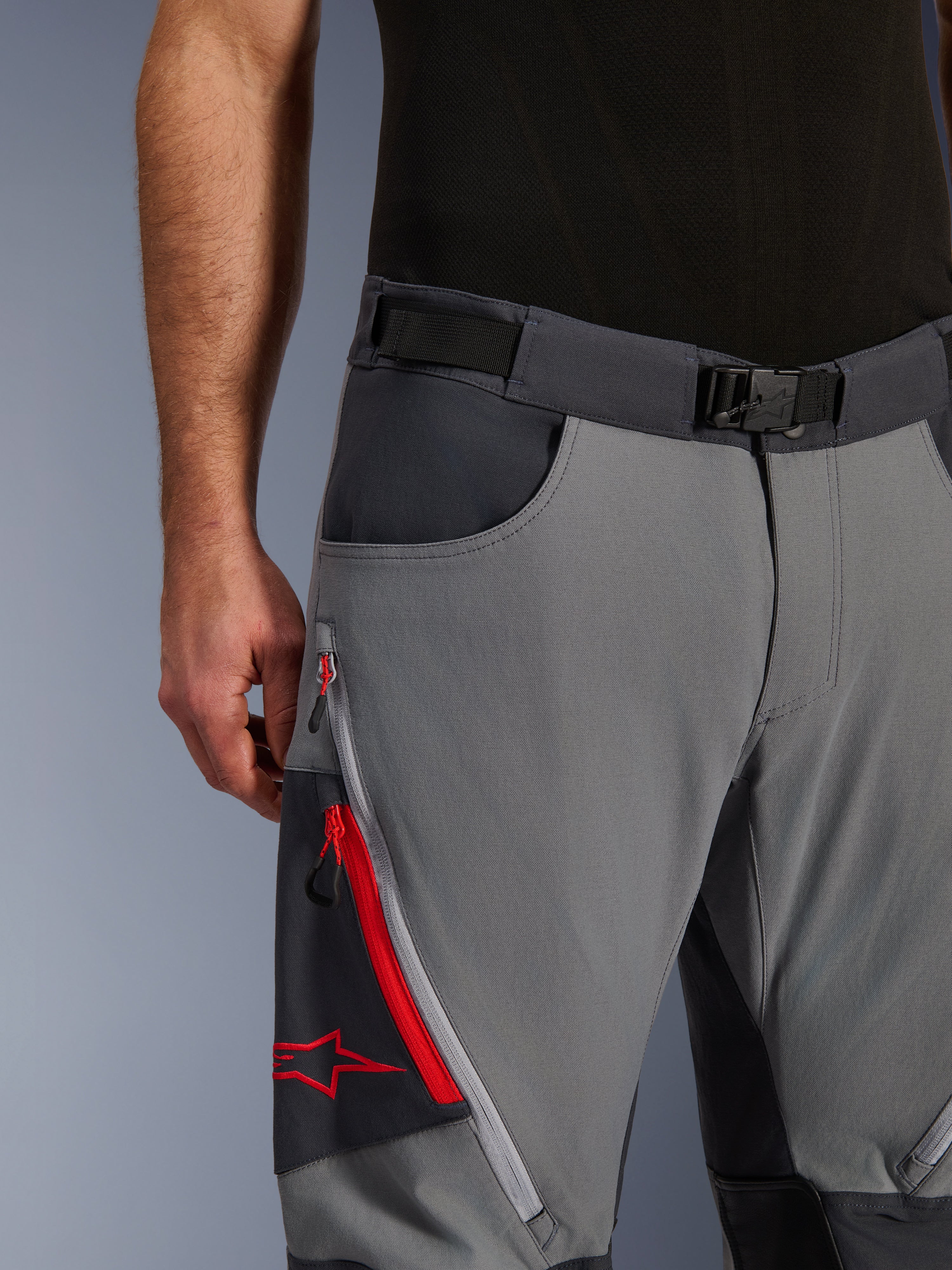 Alpinestars Maxdura Dual Pants, Adventure Motorcycle Pants, Dark Gray and Deep Gray, close-up featuring adjustable waist belt with magnetic buckle, zippered cargo pocket with red detailing and Alpinestars logo.