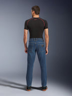 Pantalon en denim Alpinestars Flex-AST 5, bleu Indigo Washed, vue arrière montrant la coupe urbaine fuselée, porté par un mannequin avec un t-shirt technique noir et des baskets, vêtement de protection décontracté pour la moto