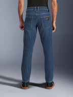 Alpinestars Flex-AST 5 Denim Pants, jeans de moto urbain pour homme en bleu indigo délavé, vue de dos montrant la coupe fuselée, les poches arrière avec écusson de la marque et la construction en denim extensible.