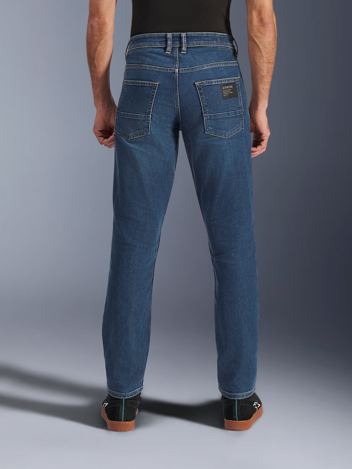Alpinestars Flex-AST 5 Denim Pants, jeans de moto urbain pour homme en bleu indigo délavé, vue de dos montrant la coupe fuselée, les poches arrière avec écusson de la marque et la construction en denim extensible.
