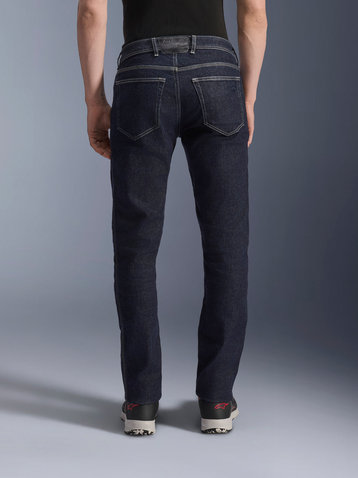 Alpinestars Copper V3 Denim Pants, men's urban motorcycle riding jeans in rinse blue, rear view showing a model wearing the straight-leg denim with a shaped back waist, tonal branding, and rear pockets.
