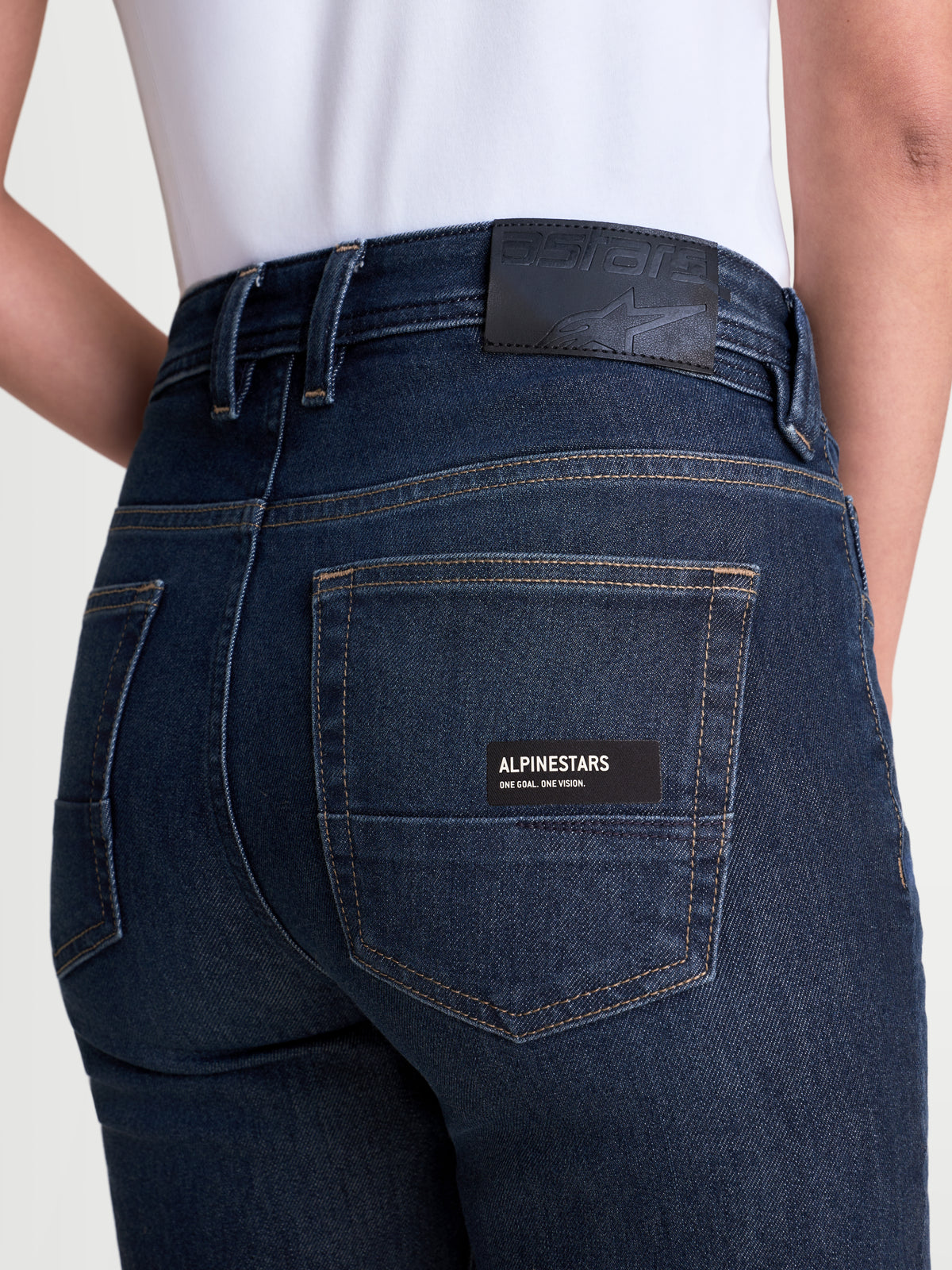 Alpinestars Stella Flex Ast 7 Denim Pantalons, pantalon de moto urbain pour femme bleu foncé, vue rapprochée de dos montrant l'écusson arrière en cuir, l'étiquette de poche de marque et la construction en denim technique monocouche porté par un modèle
