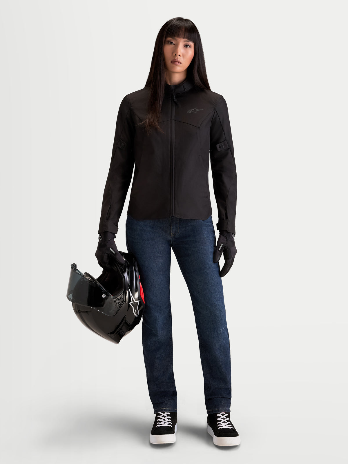 Alpinestars Stella Flex Ast 7 Denim Pantalons, pantalon moto urbain pour femme en denim bleu foncé, porté par un modèle tenant un casque et une veste assortie