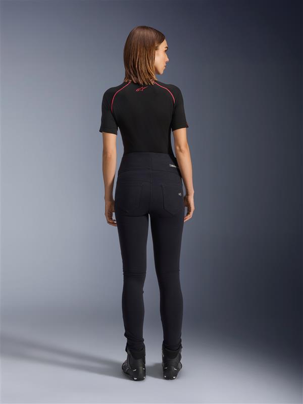 Alpinestars Stella Flex-Ast Leggings, leggings de moto pour femme, noir, vue arrière montrant la coupe slim à taille haute, portés avec un haut noir à manches courtes et des bottes de moto noires, équipement de conduite urbaine