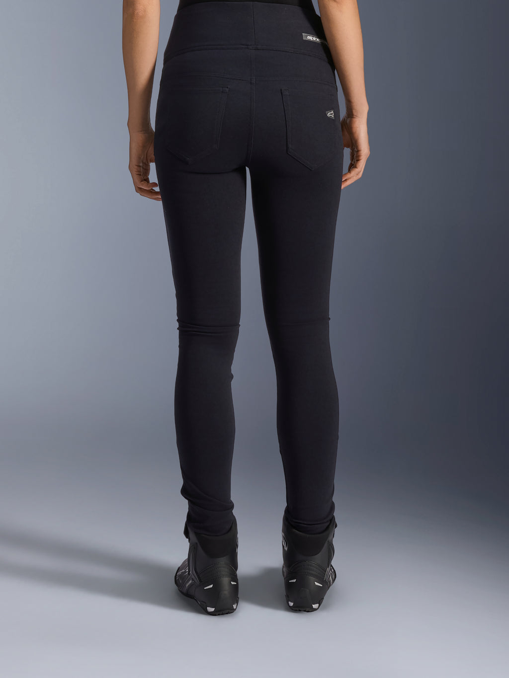 Alpinestars Stella Flex-Ast Leggings, leggings de moto pour femme, noir, vue arrière montrant les poches arrière et la coupe ajustée, portés avec des bottes de moto noires, style de conduite urbain