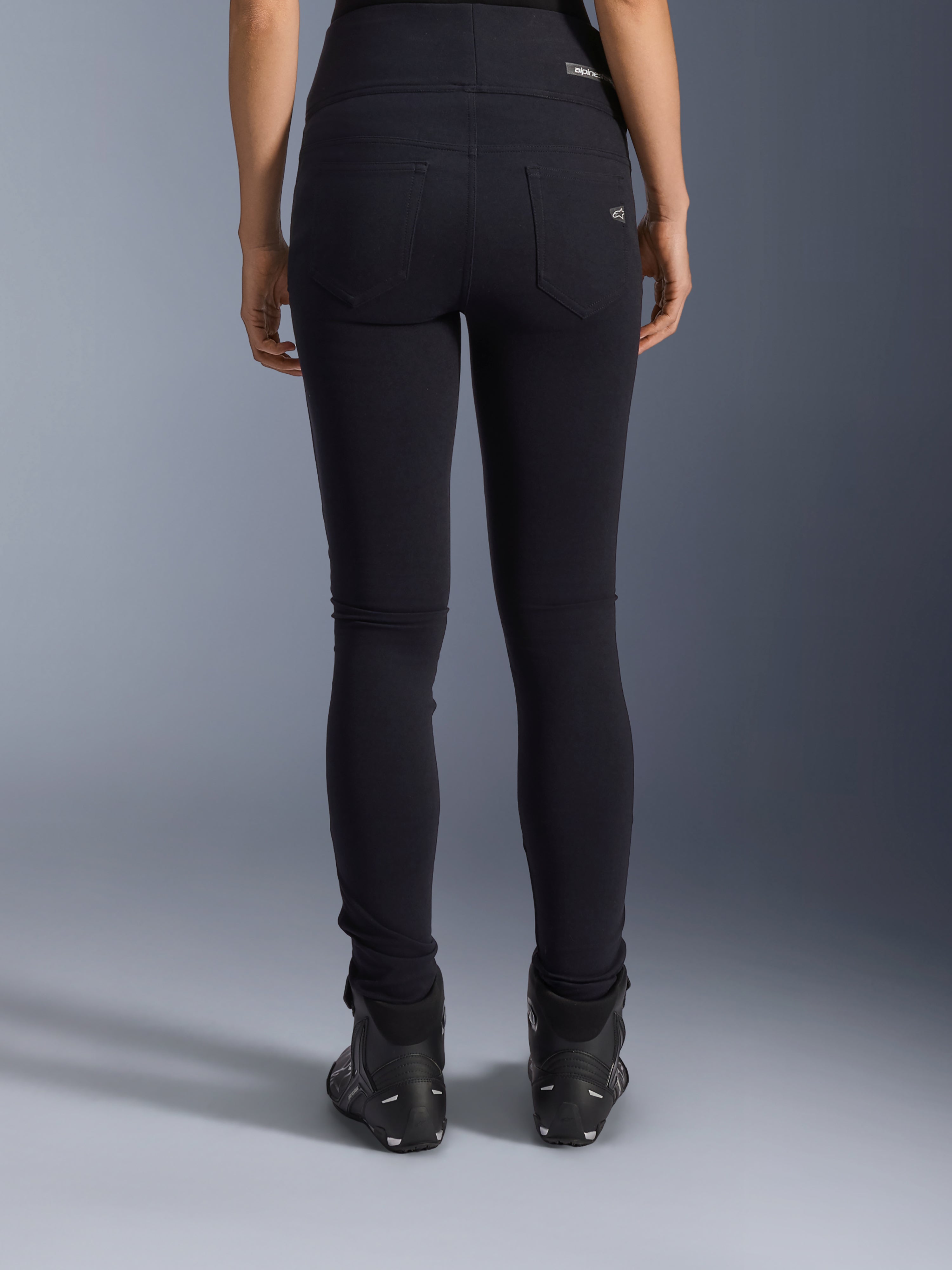 Alpinestars Stella Flex-Ast Leggings, leggings de moto pour femme, noir, vue arrière montrant les poches arrière et la coupe ajustée, portés avec des bottes de moto noires, style de conduite urbain