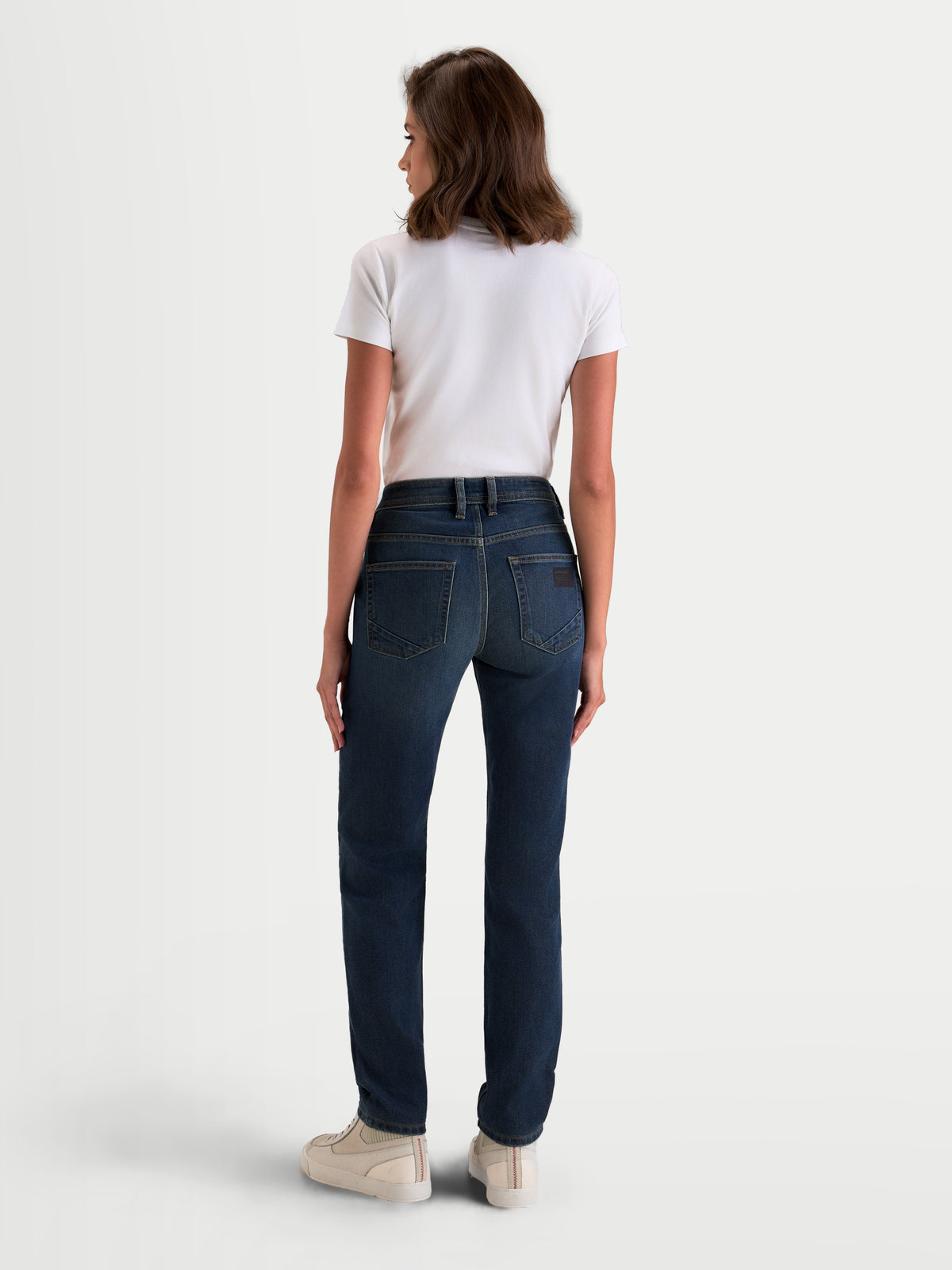 Alpinestars Stella Flex-AST 5 Denim Pants Short, women's urban motorcycle riding jeans, indigo washed blue, rear profile view on a model wearing a white top and casual sneakers, featuring a raised rear waistband and single-layer tech denim construction.